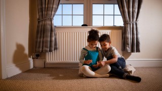 Kinder sitzen vor der Heizung Kinder sitzen vor der warmen Heizung.