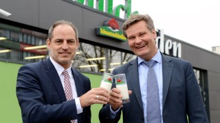 Schwarzwaldmilch-Geschäftsführer Andreas Schneider und WÄRMEPLUS-Geschäftsführer Klaus Preiser stoßen vor dem Schwarzwaldmilch-Gebäude in Freiburg mit einem Glas frischer Schwarzwaldmilch auf gutes Gelingen der Zusammenarbeit an.