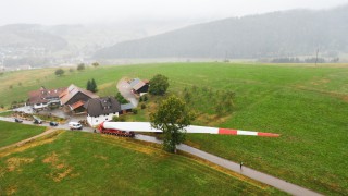 Windflügeltransport auf den Hohenlochen vorbei an einem Bauernhof