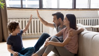 Glückliche Familie sitzt im Wohnzimmer vor Heizkörpern am Boden